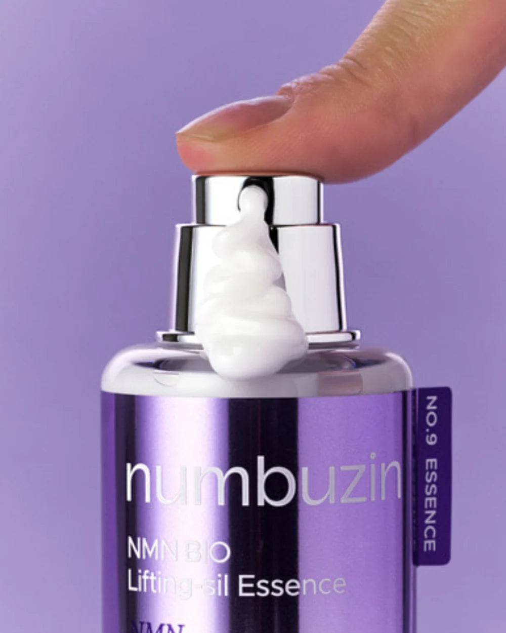 Purple bottle of Numbuzin essence with a hand holding the pump against a purple background